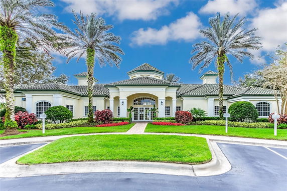Front view of a large building with a symmetrical design and a central entrance, surrounded by landscaped gardens and palm trees.