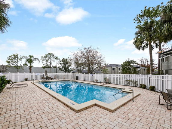 Outdoor swimming pool with surrounding fence and patio area.