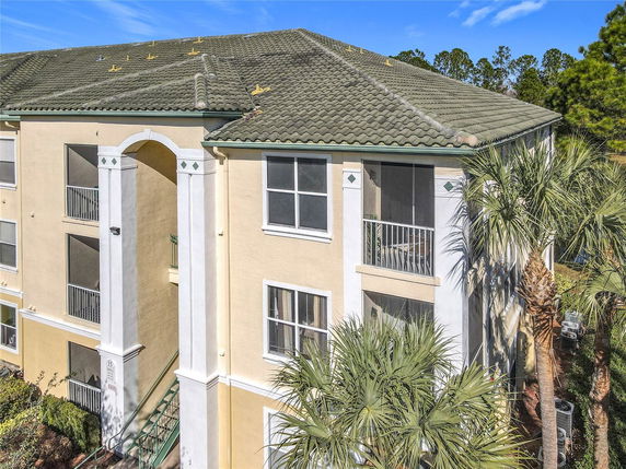 Front view of a multi-story apartment building with arched entrance and balconies.