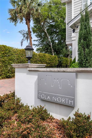 Partial view of a building with a sign reading 'Eola North' on a wall next to a lantern.