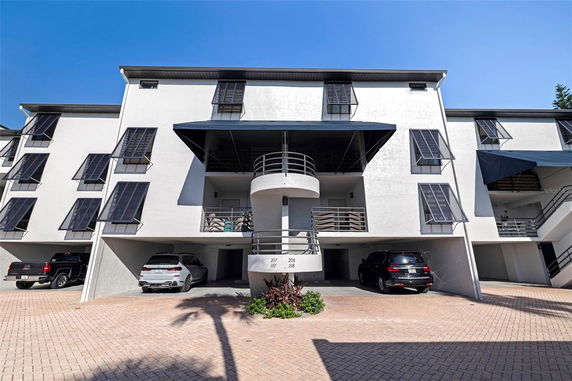 Front view of a multi-story building with balconies and shaded windows.