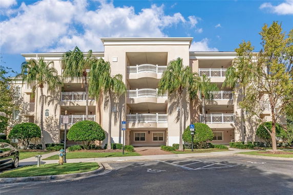 Front view of a multi-story apartment building with balconies and palm trees.