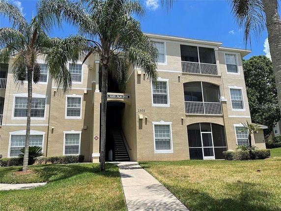 Front view of a three-story apartment building with balconies and beige exterior.