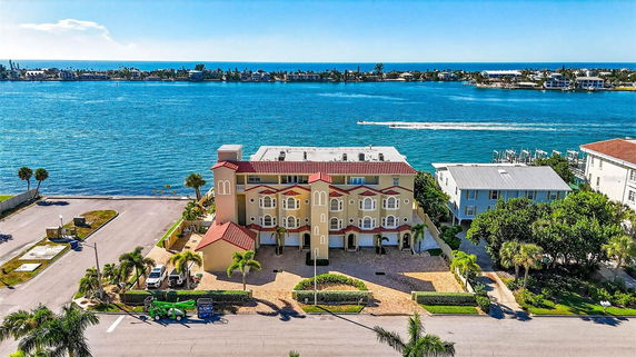 Front view of a multi-story building with a red-tiled roof, overlooking a body of water.
