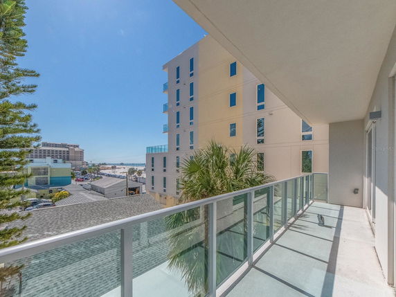View from a balcony showing adjacent buildings and a distant beach area.