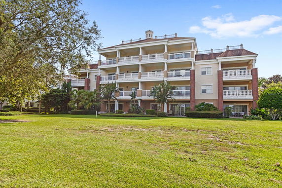 Front view of a multi-story residential building with balconies and a garden.