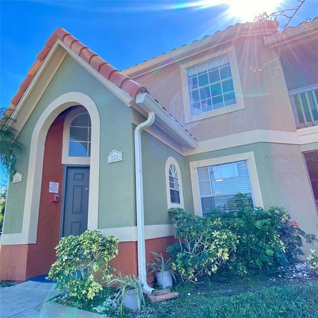 Front view of a two-story house with an arched entryway and tiled roof.