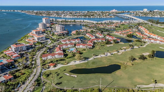 Aerial view of a coastal residential area with multiple buildings, golf courses, and waterways.