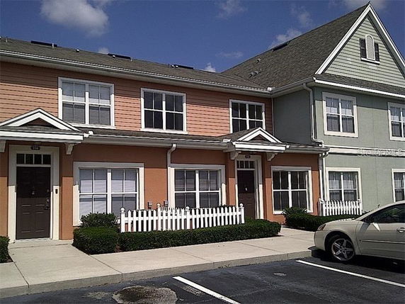 Front view of a two-story row house with a picket fence.