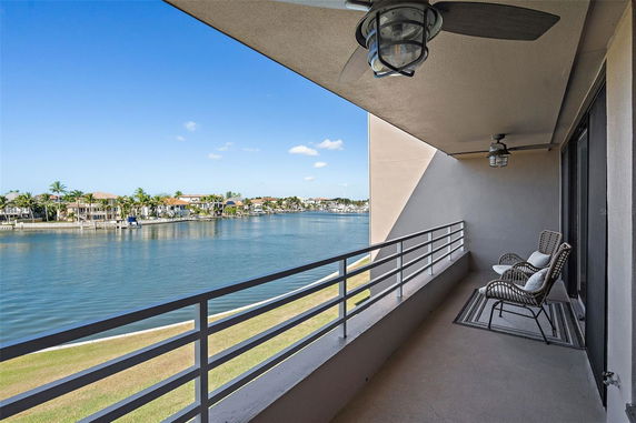 Balcony with chairs overlooking a waterfront and houses.