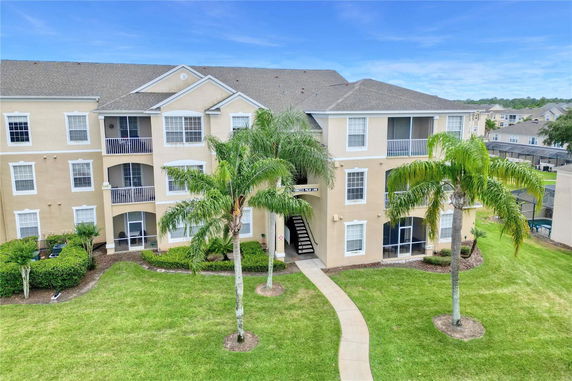 Front view of a three-story residential building with balconies and a central staircase.