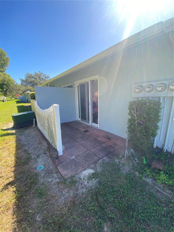 Side view of a building with sliding glass doors and a small fenced patio area.