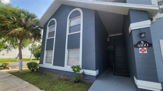 Front view of a two-story building with arched windows and an entrance staircase.