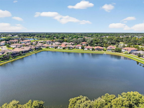 Aerial panoramic view of a suburban neighborhood with a large body of water and houses lining the waterfront.