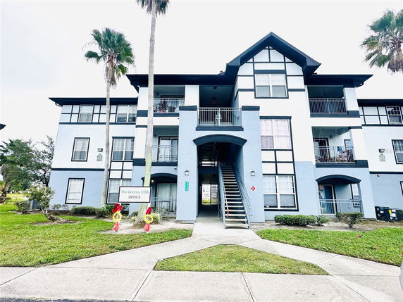 Front view of a multi-story residential building with balconies and a staircase entrance.