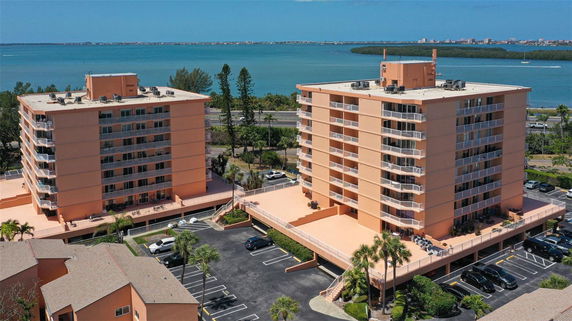 Front view of two multi-story residential buildings with balconies and parking space below.