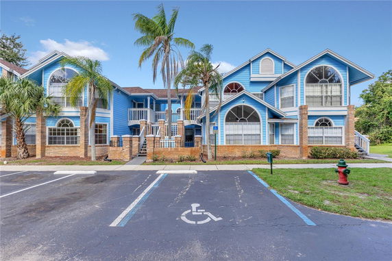 Front view of a two-story blue house with arched windows and brick accents.