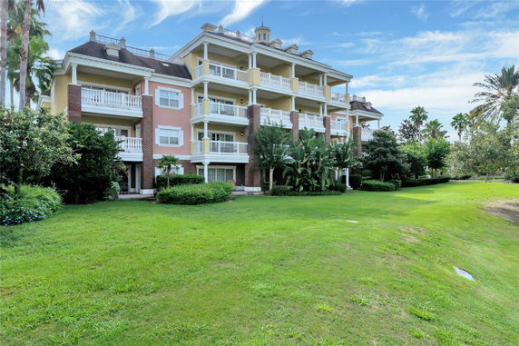 Front view of a multi-story residential building with balconies and a landscaped lawn.