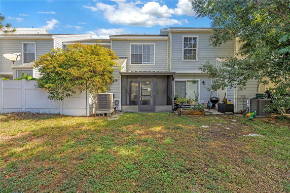Rear view of a two-story house with a porch and fencing.
