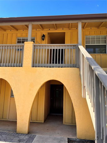 Front view of a multi-story building with a wooden exterior and arched entryway.