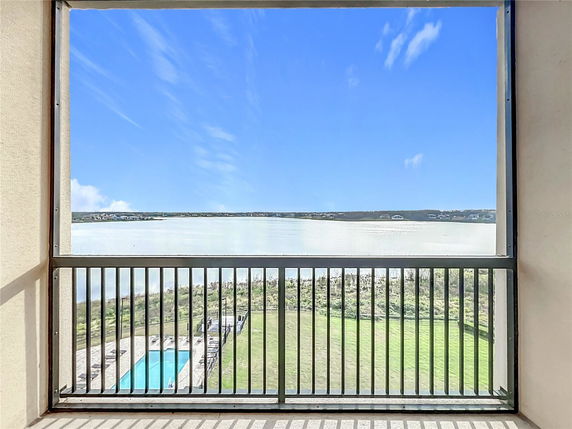 Panoramic view from a building balcony showing a lake and surrounding landscape