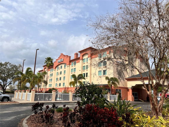 Front view of a multi-story hotel building with a paved parking area.