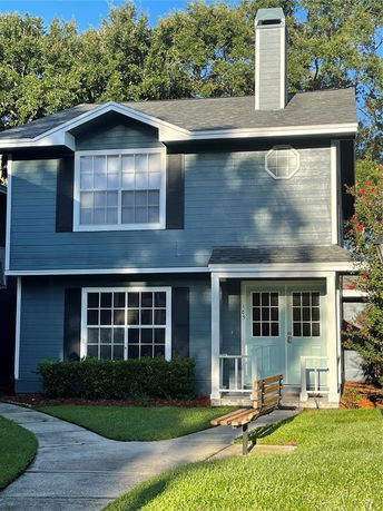 Front view of a two-story house with a chimney and blue exterior.