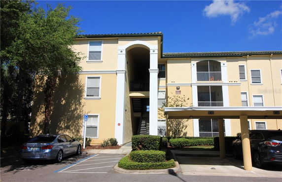 Front view of a multi-story apartment building with parking area.