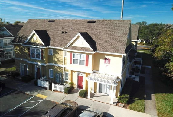 Front view of a multi-story townhouse with a pitched roof and a small white fence.