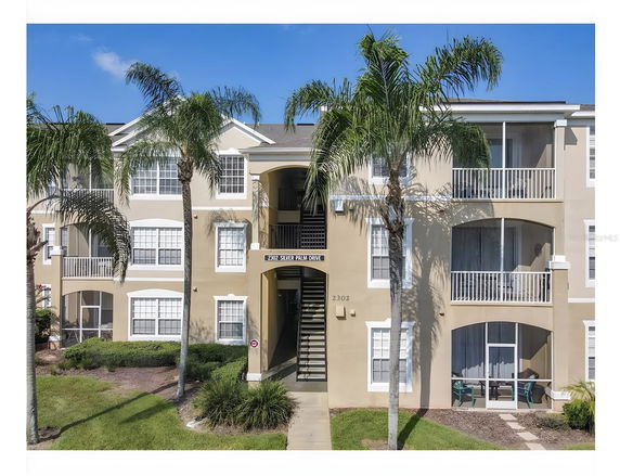 Front view of a multi-story apartment building with balconies and palm trees.