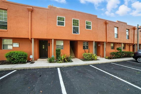 Front view of a two-story building with orange exterior and parking spaces in front.