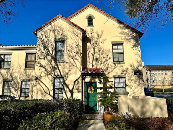 Front view of a beige two-story building with a red-tiled roof and green door.