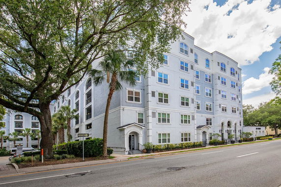 Front view of a multi-story apartment building with a light facade and multiple windows.