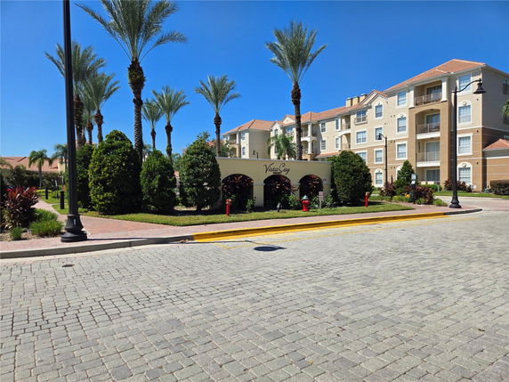Front view of a multistory building with balconies and palm trees.