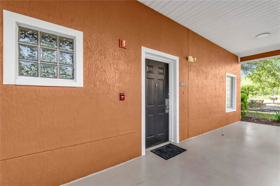 Exterior view of a building entrance with an orange wall and black door.