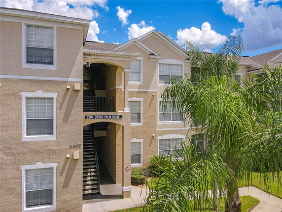 Front view of a multi-story residential building with beige exterior and multiple windows.