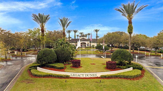 Front view of a resort-style clubhouse with palm trees and a circular driveway.