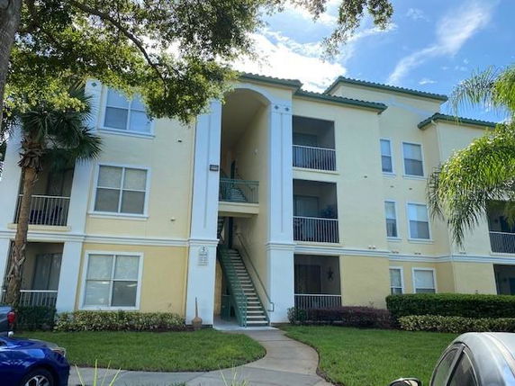 Front view of a three-story residential building with yellow walls and multiple balconies.