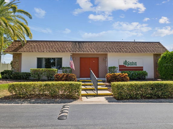 Front view of a single-story building with a shingle roof and a red door.