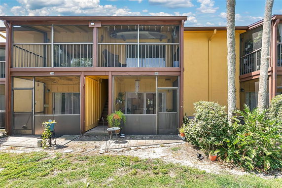 Front view of a two-story building with screened balconies and patio areas.