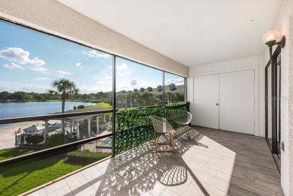Enclosed balcony with a view of a lake and surrounding landscape.