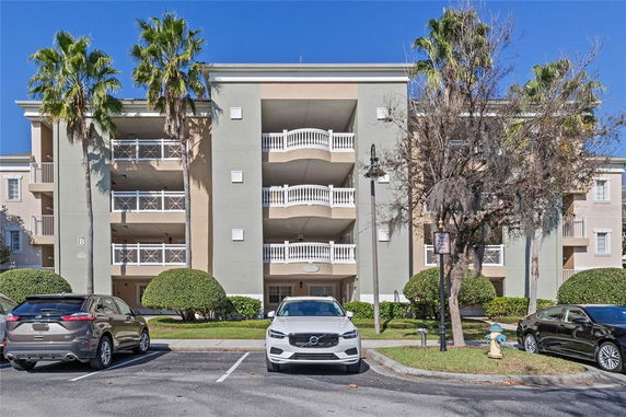 Front view of a multi-story residential building with balconies and parking area.