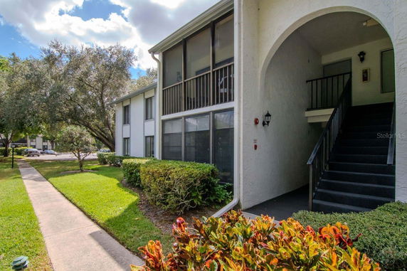 Front view of a two-story building with exterior staircase and screened balcony.