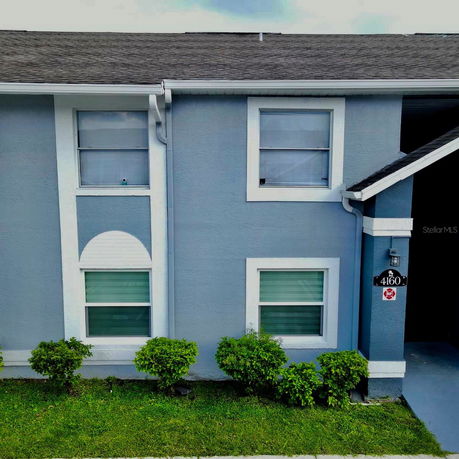 Front view of a blue two-story house with white trim and four windows.