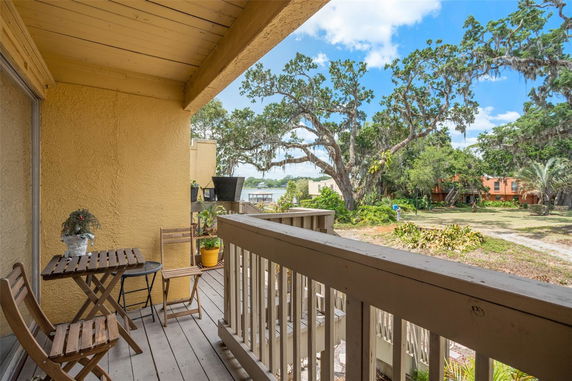 Balcony view with chairs and a small table overlooking trees and open area.