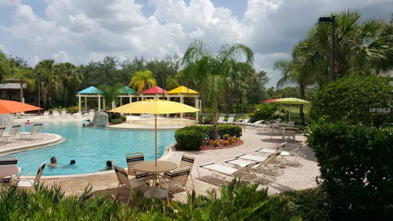 Outdoor swimming pool with lounge chairs and umbrellas around it.