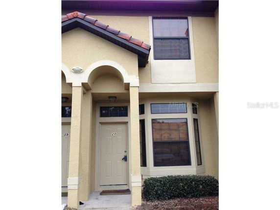 Front view of a two-story house with beige exterior and an arched entrance.