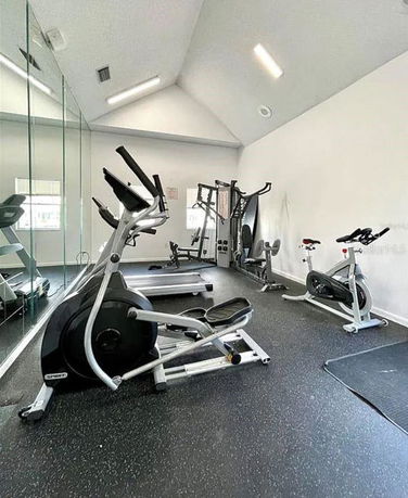 Indoor gym area with exercise equipment including cycles, elliptical, and weight machines.