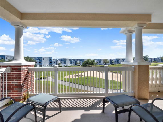 View from a balcony showing a grassy area and distant buildings.