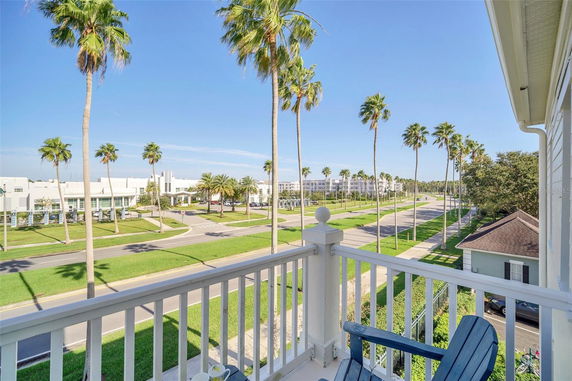 Panoramic view from a balcony showing palm trees and a road.